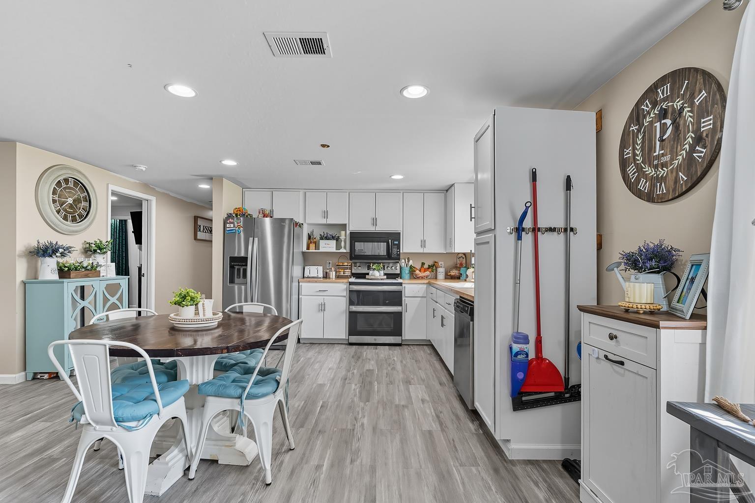 2436 Renfroe Road Pace, FL 32571 - Photo 13 of 45 a kitchen with stainless steel appliances a dining table chairs stove and cabinets