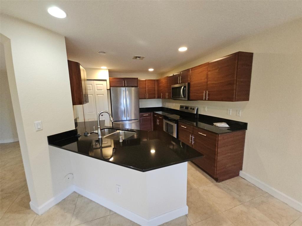 6185 Laurel Lane, Unit B Tamarac, FL 33319 - Photo 4 of 12 a kitchen with stainless steel appliances granite countertop a sink a stove and a refrigerator