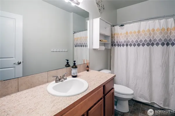 a bathroom with a granite countertop sink toilet and a mirror
