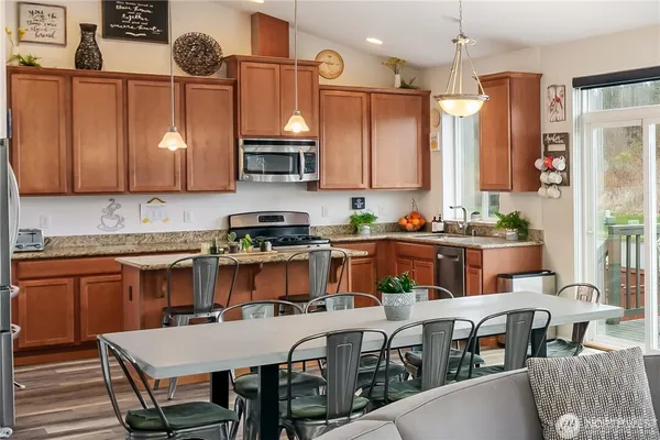 a view of kitchen with stainless steel appliances granite countertop a table chairs sink and cabinets