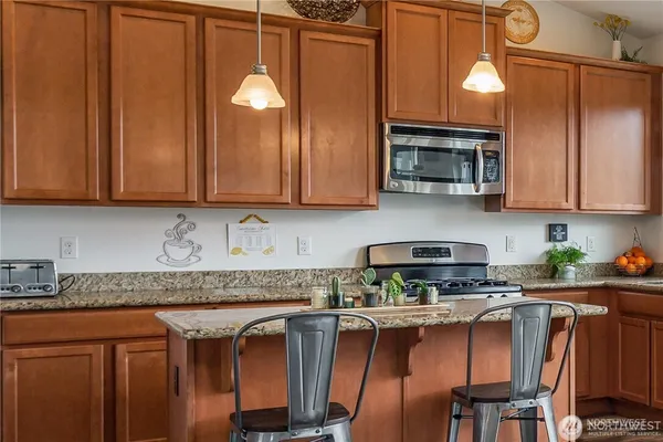 a kitchen with stainless steel appliances granite countertop wooden cabinets a stove top oven