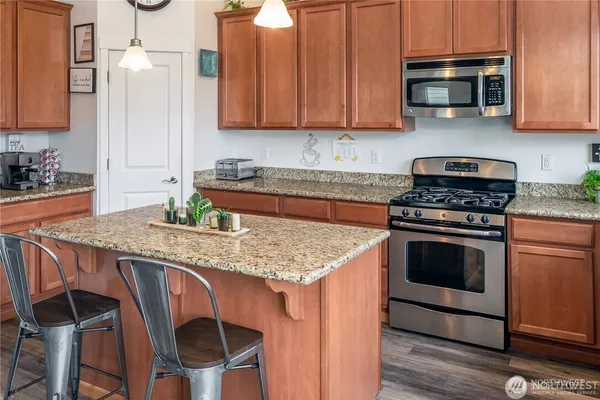 a kitchen with stainless steel appliances granite countertop a stove a sink and a microwave