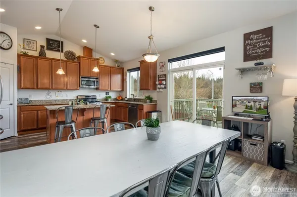 a kitchen with stainless steel appliances granite countertop a stove a refrigerator a oven a sink with a dining table and chairs