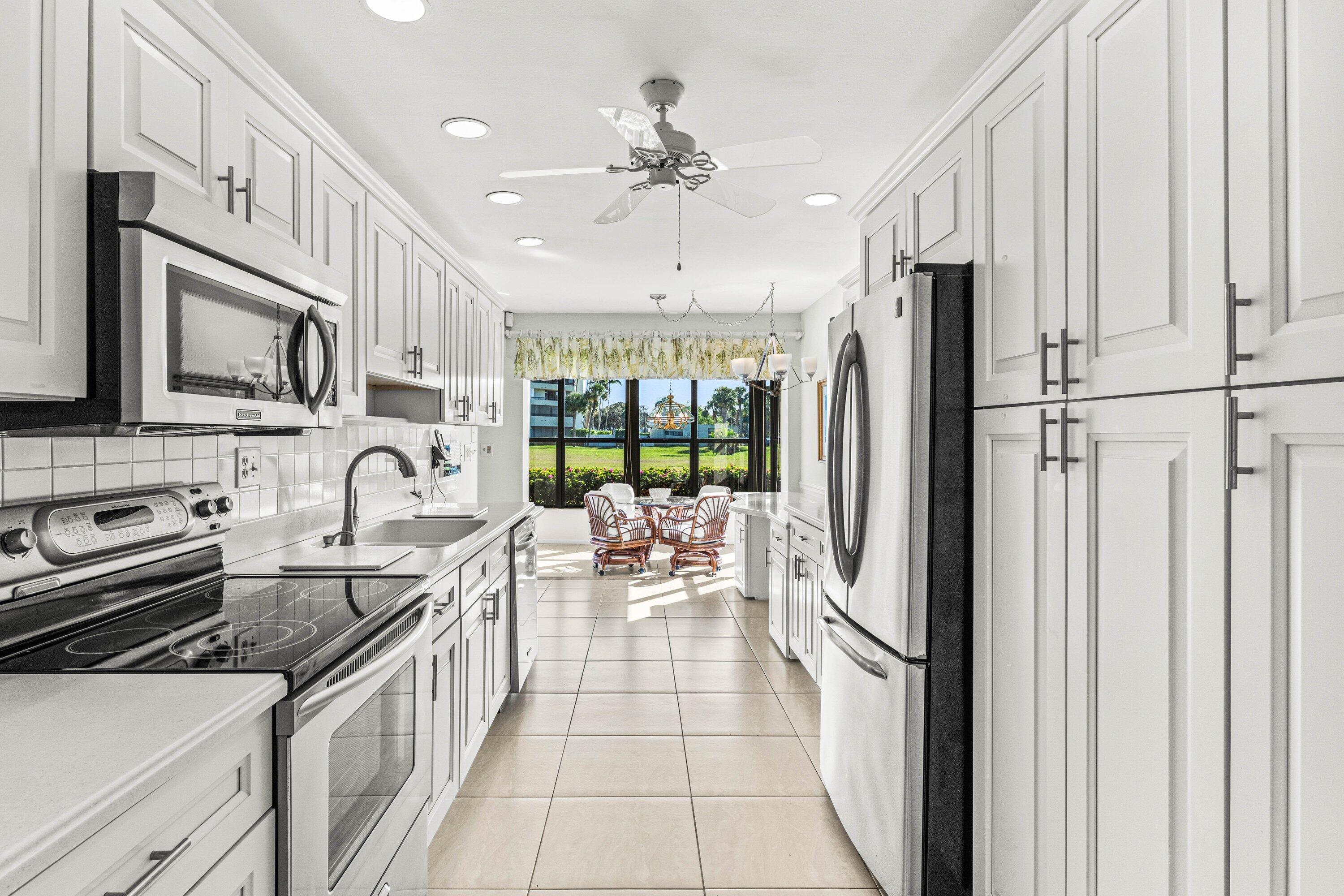 6426 Casabella Lane Boca Raton, FL 33433 - Photo 11 of 42 a kitchen with stainless steel appliances granite countertop a refrigerator a stove and a sink with large window