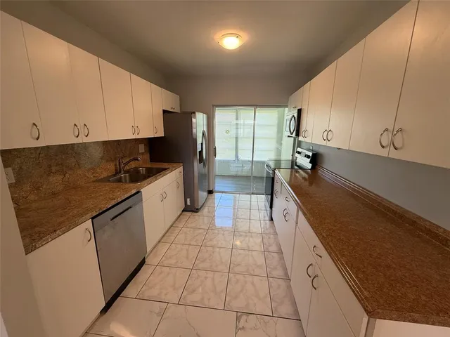 a large kitchen with kitchen island granite countertop a sink a counter top space and cabinets
