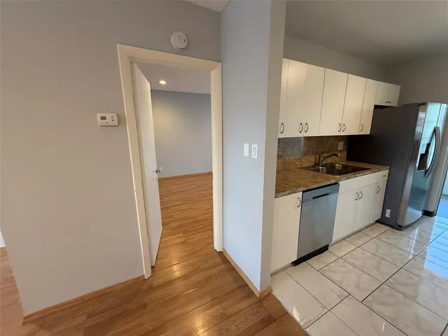 a view of a kitchen with refrigerator and wooden floor