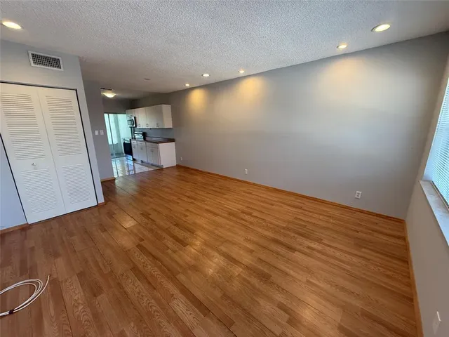 an empty room with wooden floor and a large window