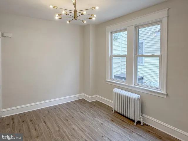 an empty room with wooden floor chandelier fan and windows