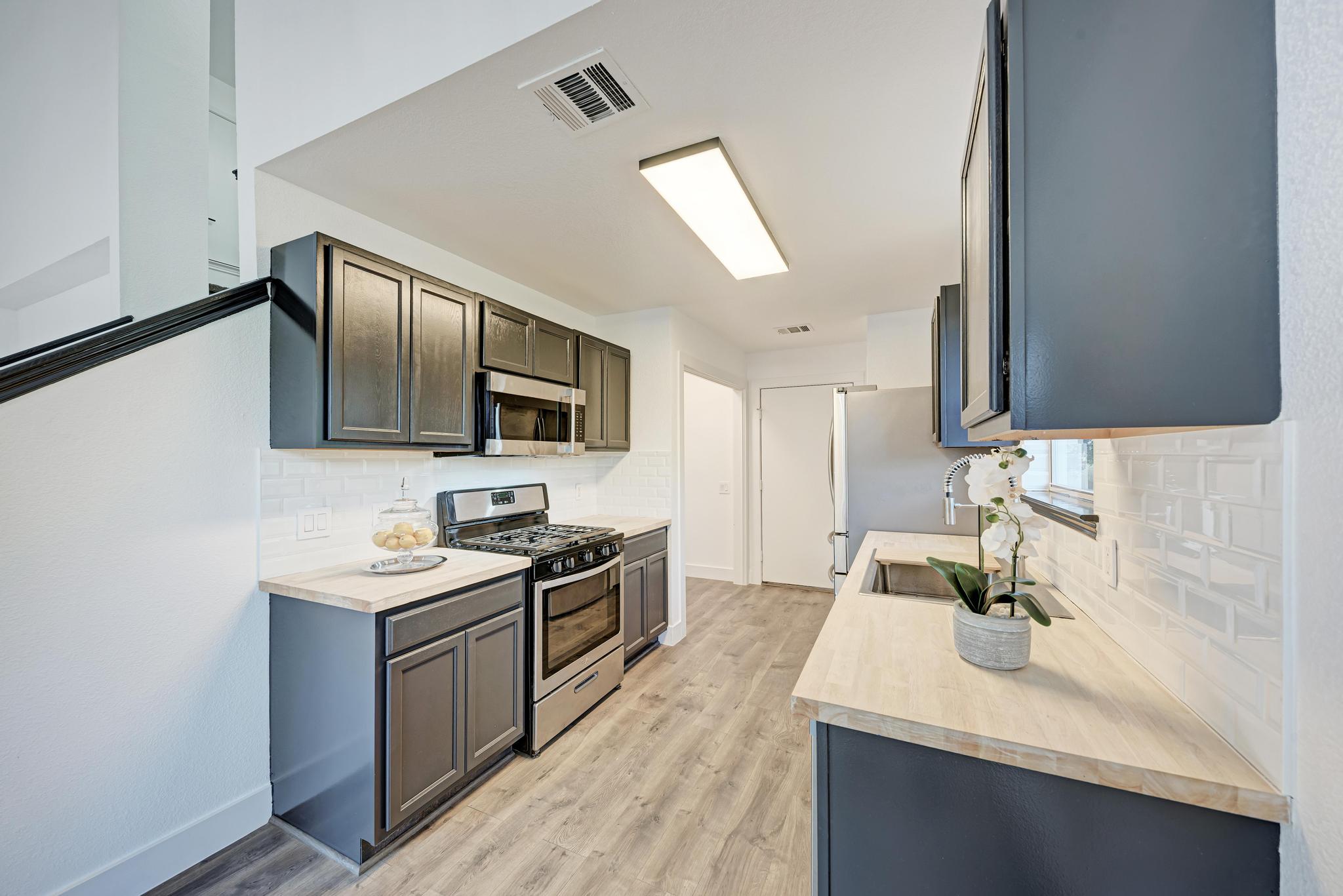 18108 Belfry Pass Manor, TX 78653 - Photo 19 of 40 a kitchen with stainless steel appliances granite countertop a sink stove microwave and refrigerator