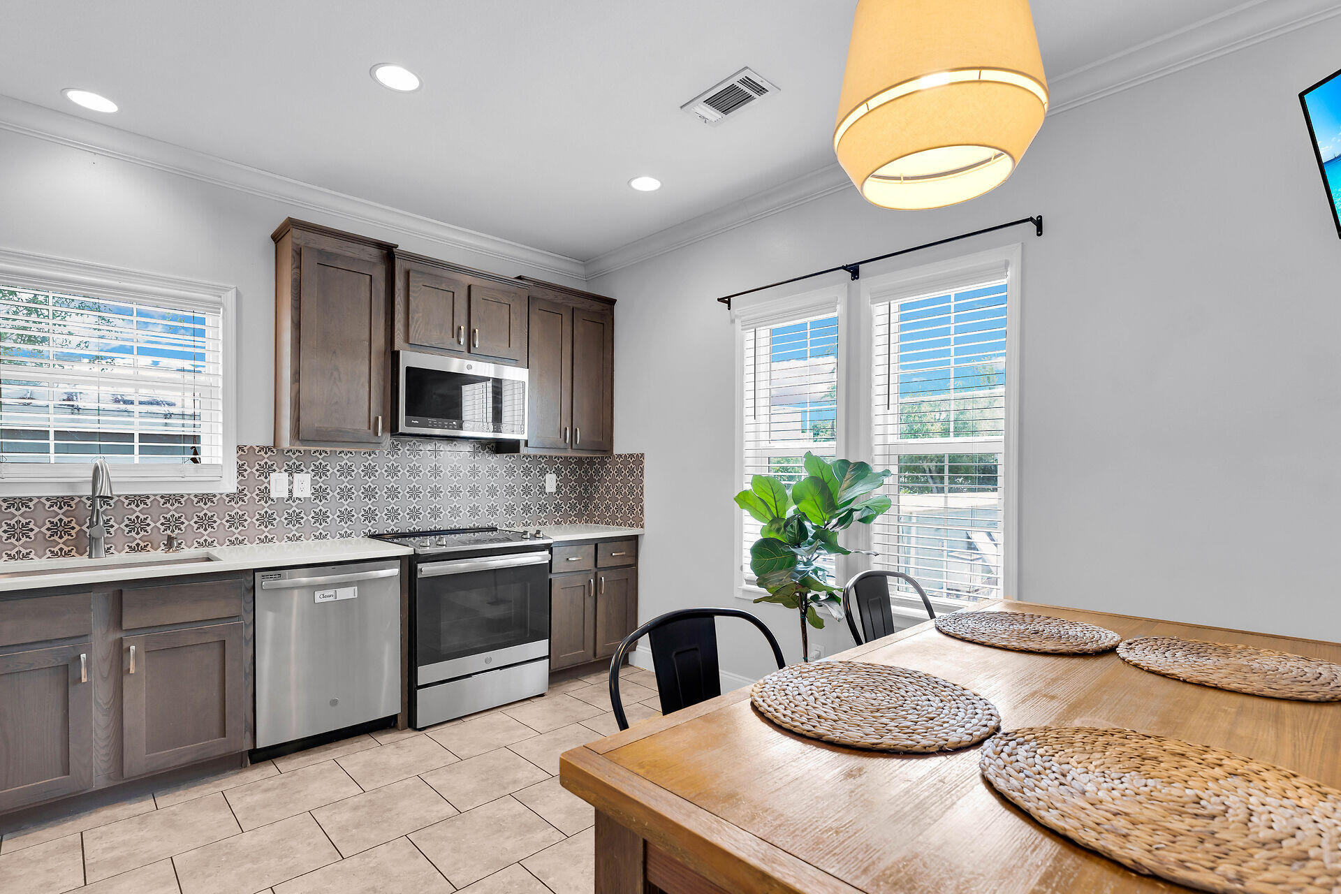 59 Ed Swift Road Key West, FL 33040 - Photo 10 of 35 a kitchen with stainless steel appliances granite countertop a sink a stove a dining table and chairs with wooden floor
