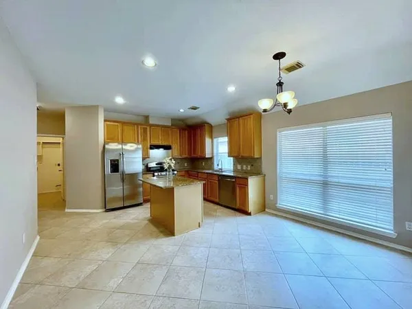a kitchen with stainless steel appliances kitchen island granite countertop a refrigerator and a sink