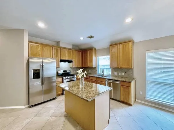 a kitchen with stainless steel appliances granite countertop a stove top oven a refrigerator a sink and dishwasher