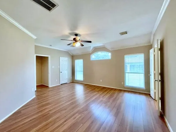 an empty room with wooden floor chandelier fan and windows