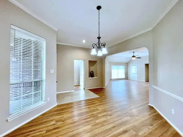 a view of a room with wooden floor chandelier and windows