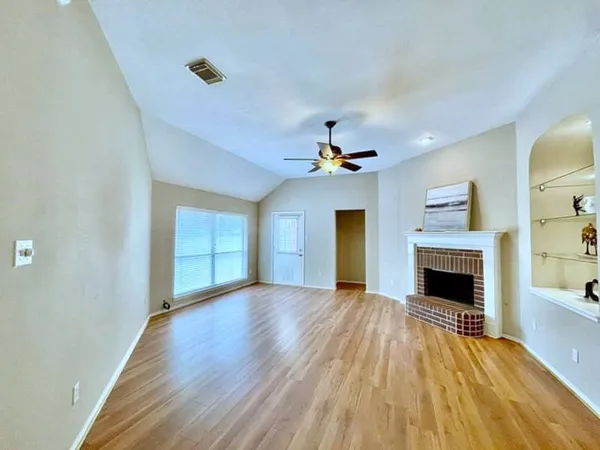 wooden floor fireplace and windows in an empty room