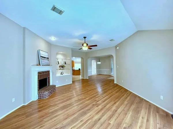 a view of a livingroom with a fireplace a chandelier fan and wooden floor
