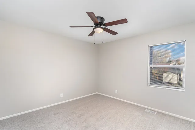 an empty room with a window and ceiling fan