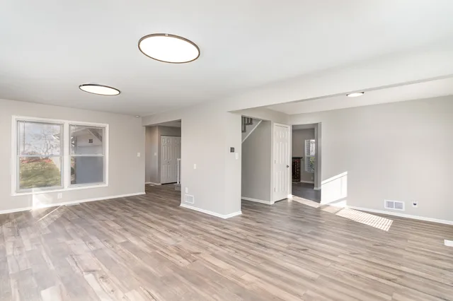 a view of an empty room with wooden floor and window