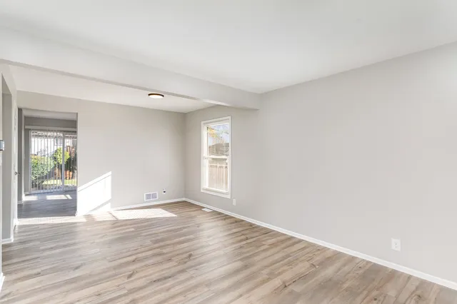 a view of an empty room with wooden floor and a window