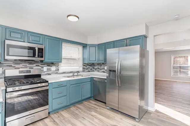 a kitchen with stainless steel appliances granite countertop a stove top oven a sink and a refrigerator