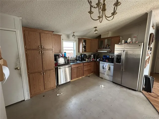 a kitchen with stainless steel appliances granite countertop a refrigerator a sink a stove and white cabinets