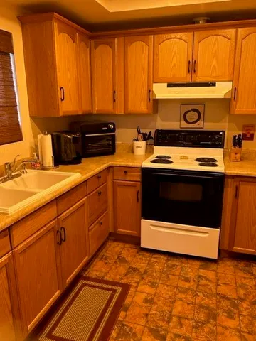 a utility room with stainless steel appliances granite countertop a stove a sink and a microwave