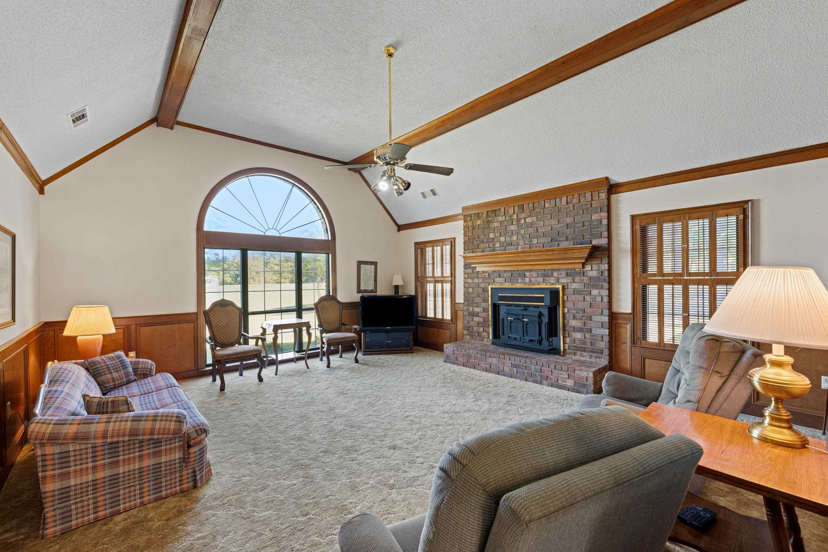 650 Blain Road Rossville, TN 38066 - Photo 7 of 26 This spacious living room features soaring vaulted ceilings and a large window that bathes the space in natural light while overlooking the serene yard. The brick fireplace adds character and a cozy focal point, making this a comfortable gathering space.