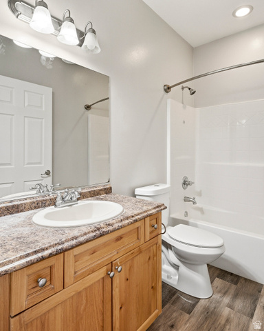 1177 Northfield Road, Unit 26 Cedar City, UT 84721 - Photo 30 of 45 Bathroom featuring a natural wood-finish vanity with a built-in sink, a speckled countertop, a large mirror, and a full bathtub with a shower
