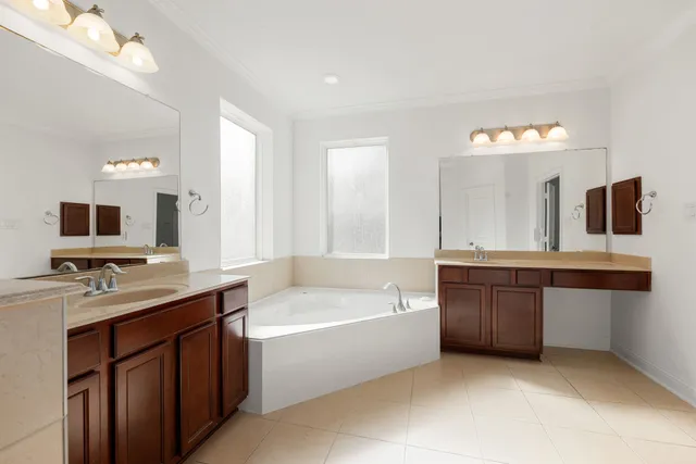 a bathroom with a bathtub a double vanity sink and mirror
