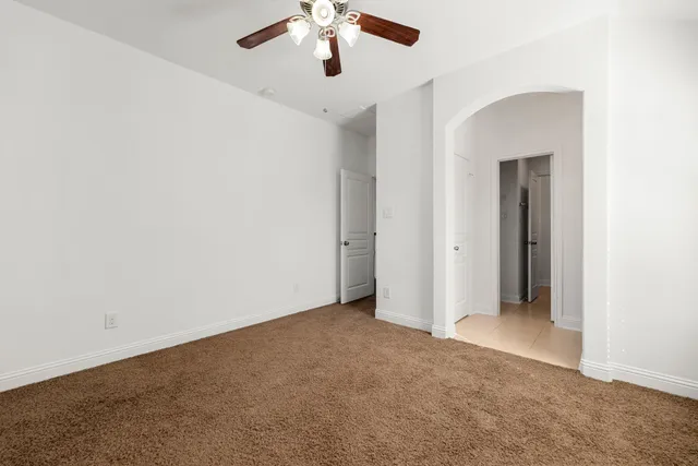 an empty room with a ceiling fan and carpet