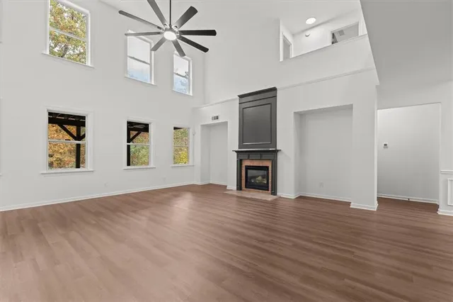 a view of an empty room with wooden floor and a ceiling fan