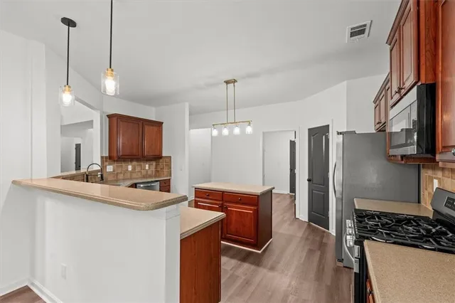 a large kitchen with a sink and dishwasher a stove top oven with wooden floor