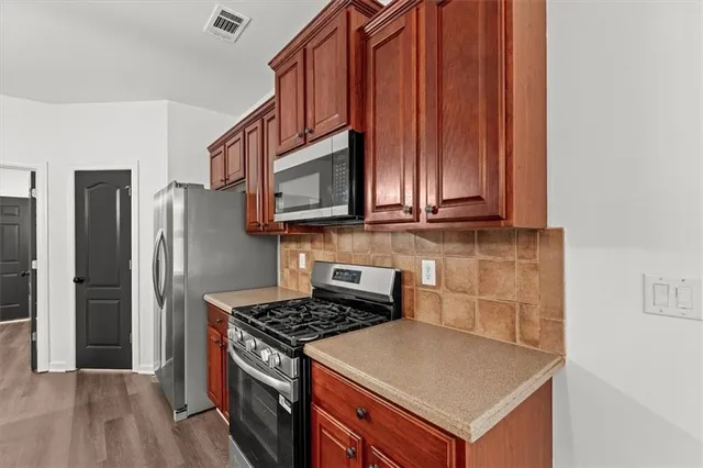 a kitchen with stainless steel appliances granite countertop a sink a stove and a wooden floor