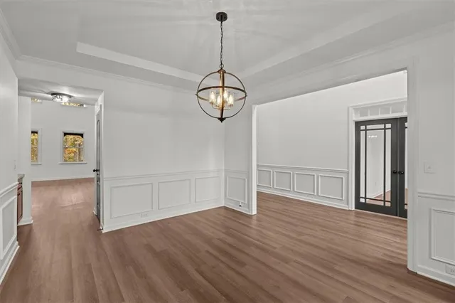 a view of a room with wooden floor chandelier and windows