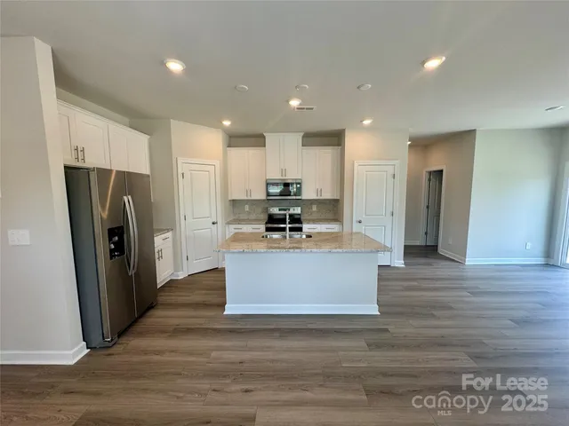 a view of kitchen with stainless steel appliances granite countertop a stove a refrigerator a sink and a oven