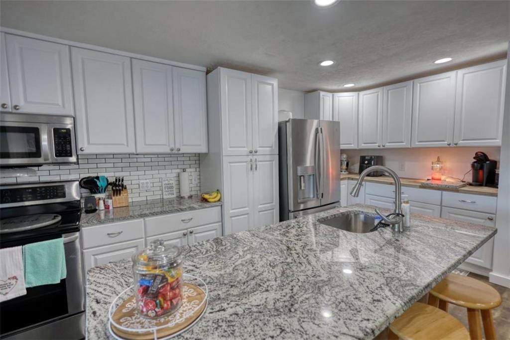 89 Miss Sarah Road Monticello, GA 31064 - Photo 25 of 77 a kitchen with stainless steel appliances granite countertop a sink a stove a refrigerator a microwave and cabinets