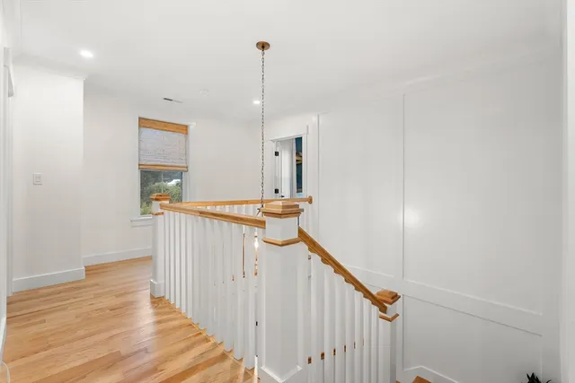 a view of a hallway with wooden floor and staircase