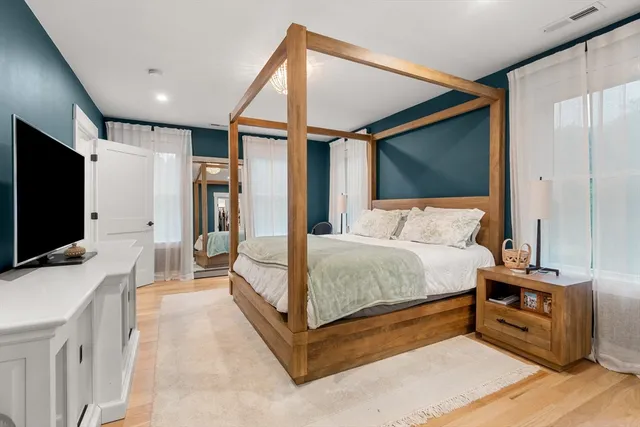 a bedroom with a bed and a flat tv screen on wall