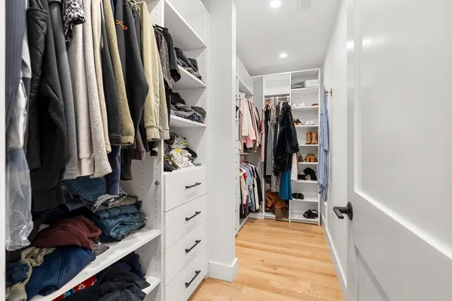 a view of walk in closet with clothes and shoes