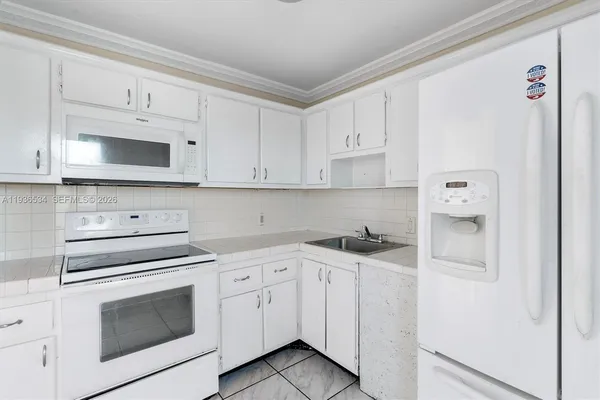a kitchen with white cabinets and white appliances