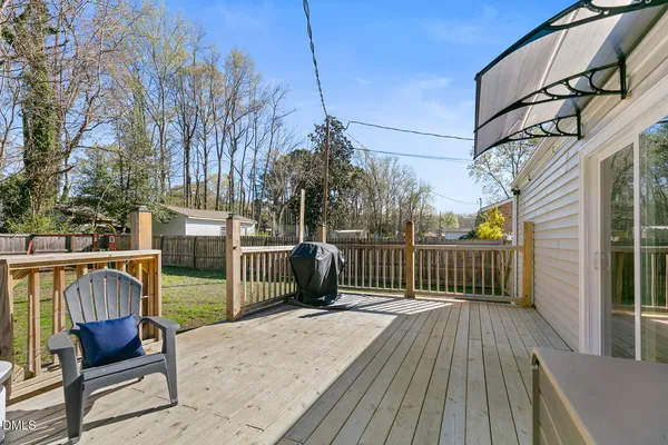 a view of a deck with wooden floor and bench next to a yard