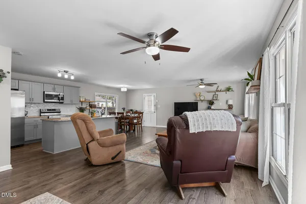 a living room with furniture kitchen view and a chandelier