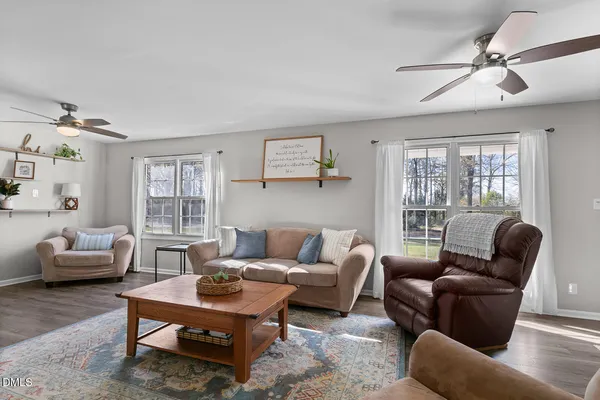 a living room with furniture a rug potted plant and a window