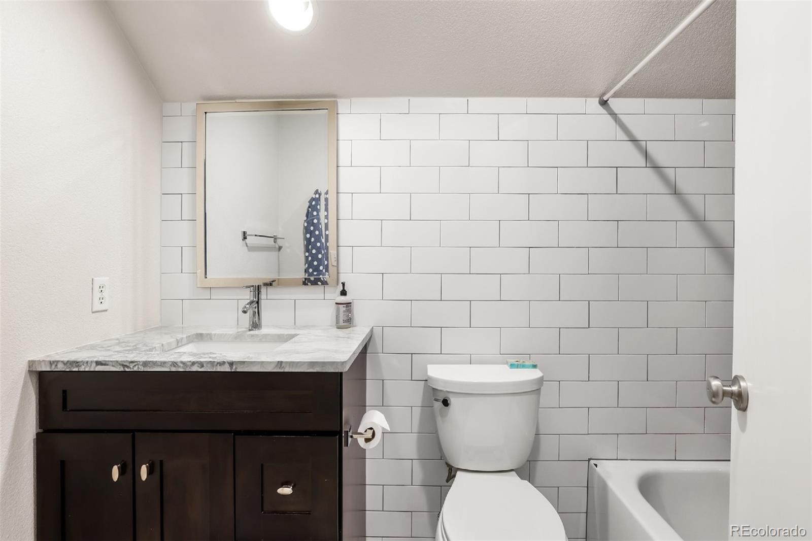 1947 King Street Denver, CO 80204 - Photo 18 of 40 a bathroom with a granite countertop toilet sink and mirror