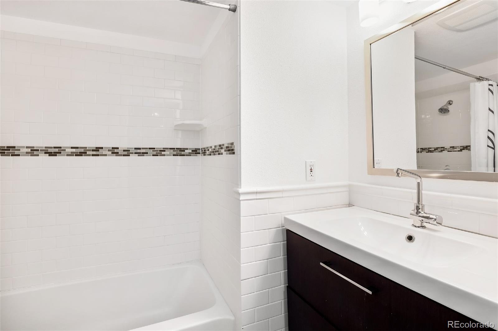 1947 King Street Denver, CO 80204 - Photo 24 of 40 a bathroom with a double vanity sink a mirror and shower