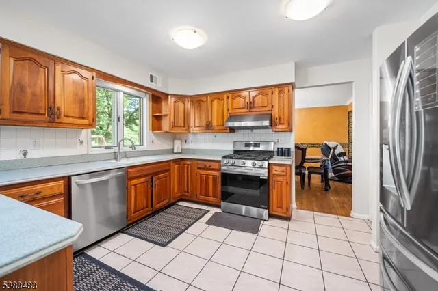 a kitchen with stainless steel appliances granite countertop a refrigerator stove top oven and sink
