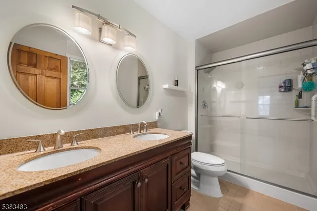 a bathroom with a granite countertop double vanity sink mirror and toilet