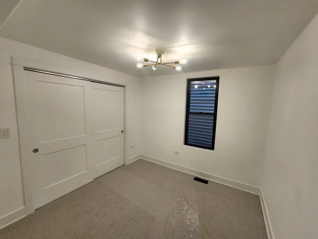 an empty room with chandelier fan and windows