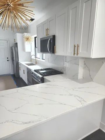 a kitchen with stainless steel appliances kitchen island granite countertop a sink a stove and a microwave oven in a white refrigerator