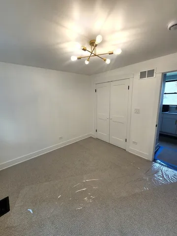 an empty room with chandelier fan and windows